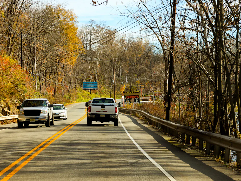 Cars on a road between autumn trees