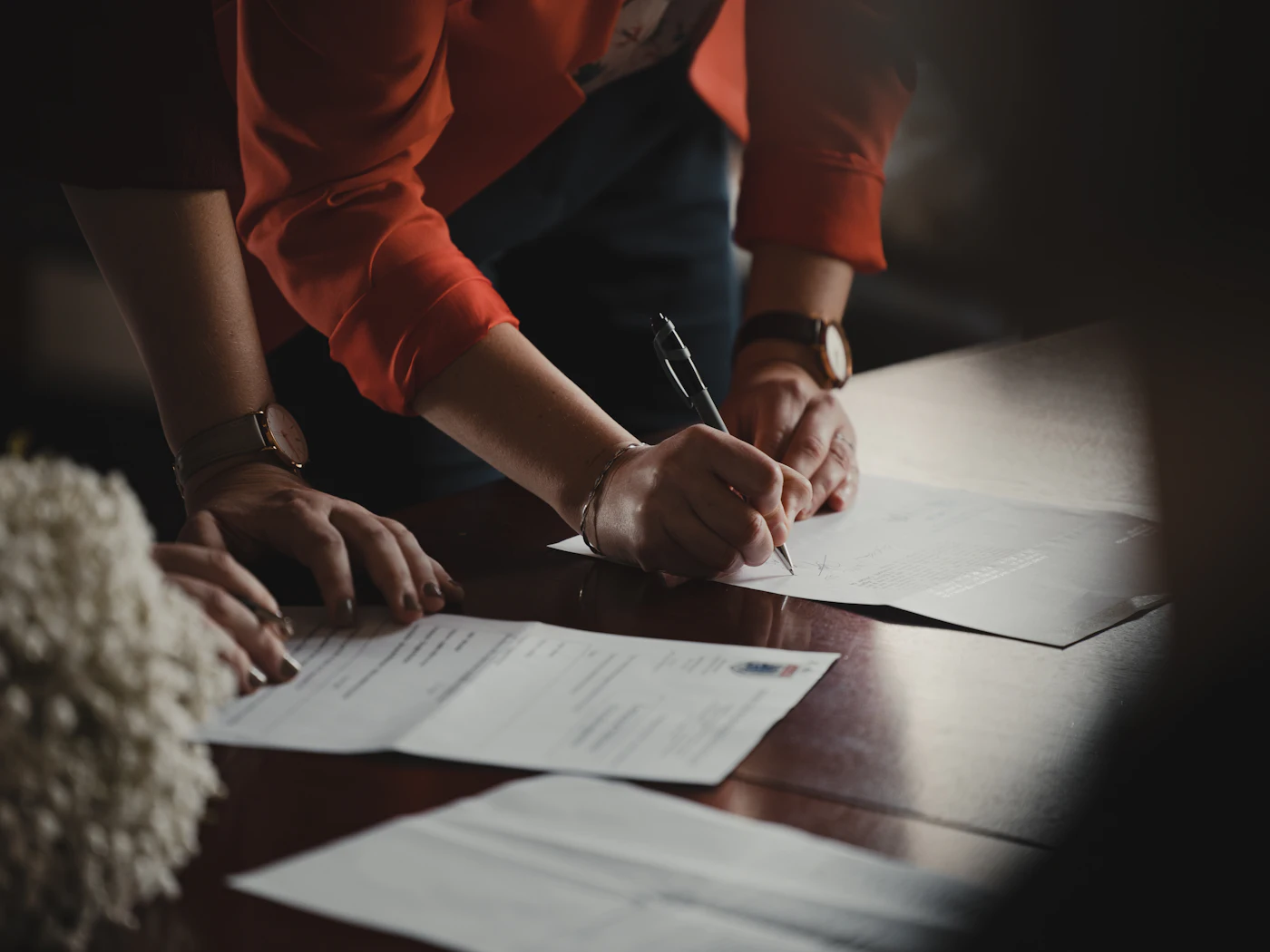A person signing paperwork at a desk